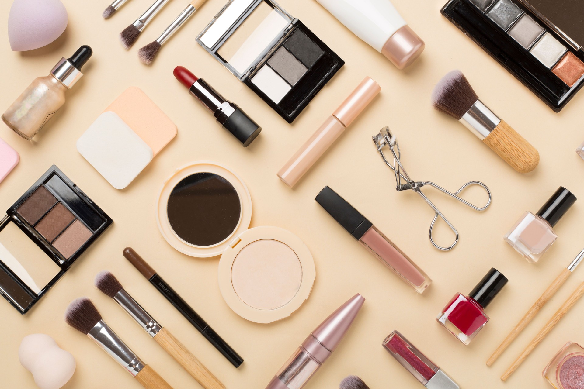 Flat lay with makeup products and tools on color background